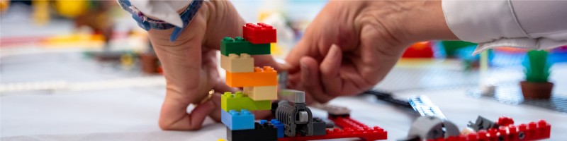 Mani che costruiscono con i mattoncini Lego durante un laboratorio (foto Debora Tomasi)